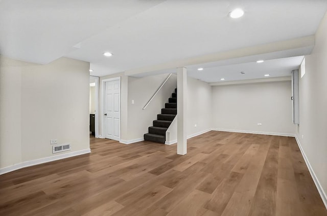 finished below grade area with visible vents, light wood-style flooring, recessed lighting, baseboards, and stairs