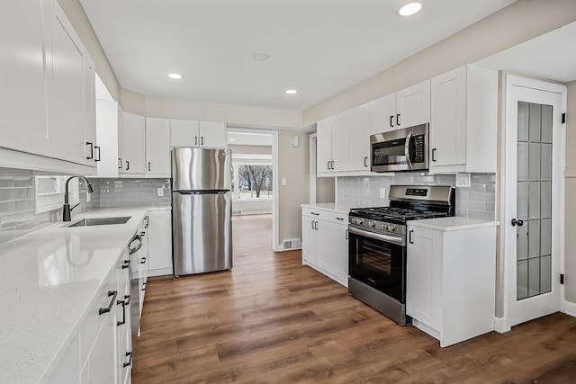 kitchen with a sink, dark wood-style flooring, white cabinetry, and stainless steel appliances