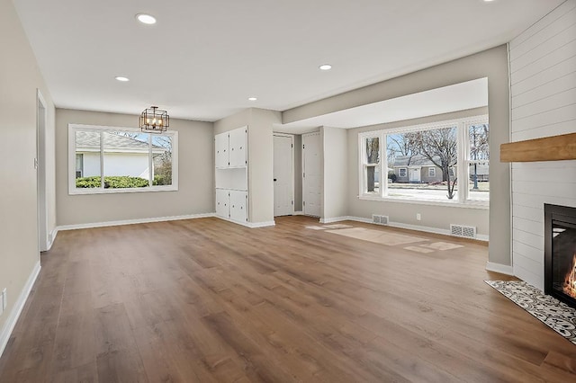 unfurnished living room with visible vents, baseboards, wood finished floors, and a fireplace