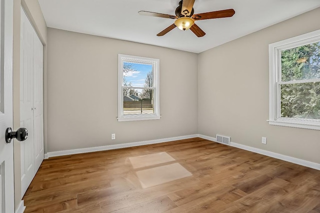 unfurnished bedroom featuring a ceiling fan, wood finished floors, baseboards, visible vents, and a closet