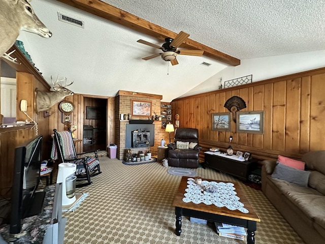 carpeted living area featuring visible vents, lofted ceiling with beams, wood walls, ceiling fan, and a textured ceiling