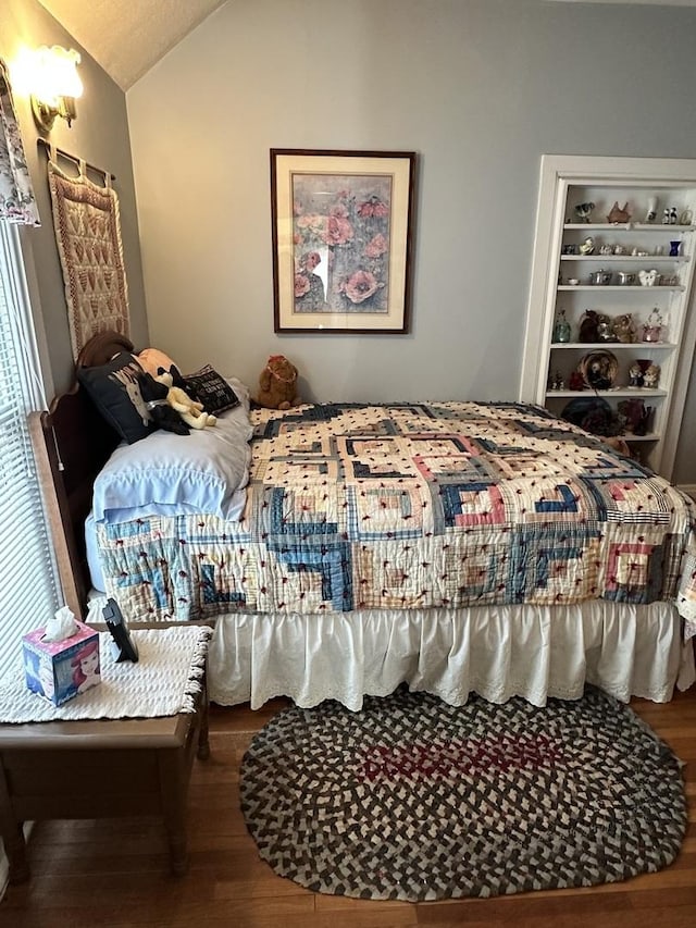 bedroom with vaulted ceiling and wood finished floors