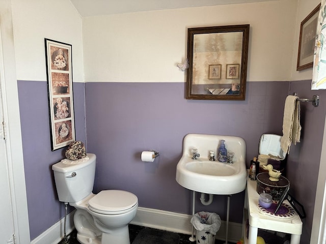 bathroom featuring a wainscoted wall, a sink, toilet, and tile walls