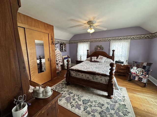 bedroom with a ceiling fan, vaulted ceiling, and wood finished floors