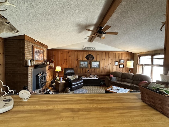 unfurnished living room with vaulted ceiling with beams, wood walls, a textured ceiling, and wood finished floors