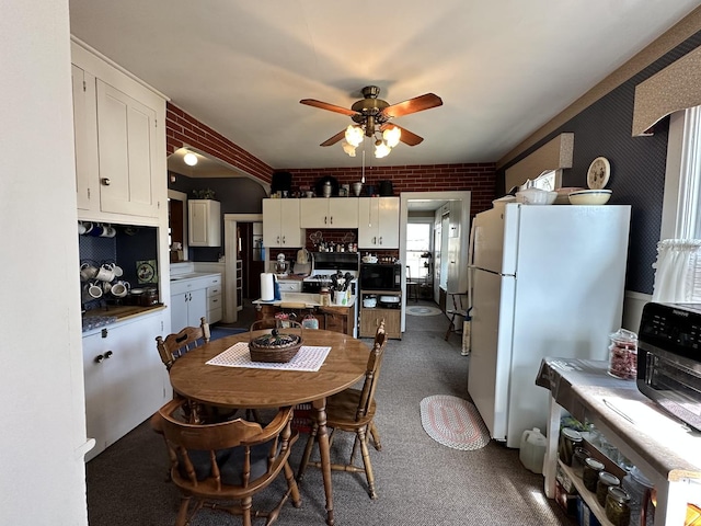 dining area featuring brick wall and a ceiling fan