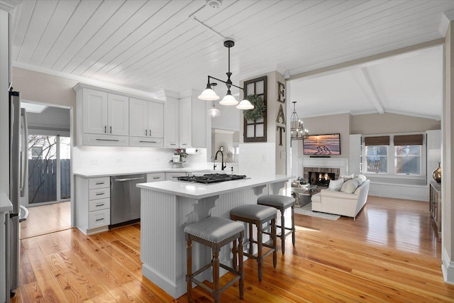 kitchen with a healthy amount of sunlight, appliances with stainless steel finishes, a kitchen breakfast bar, and light countertops