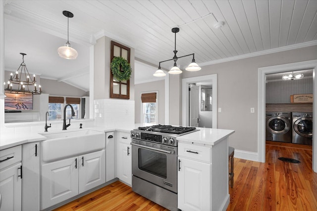 kitchen featuring stainless steel gas range oven, washing machine and dryer, light wood-style flooring, a sink, and crown molding