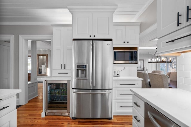 kitchen with wine cooler, crown molding, light wood finished floors, appliances with stainless steel finishes, and a chandelier