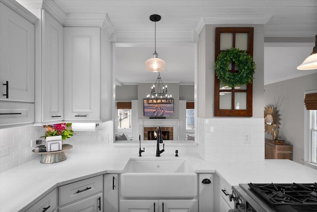 kitchen featuring a sink, white cabinetry, ornamental molding, tasteful backsplash, and gas range