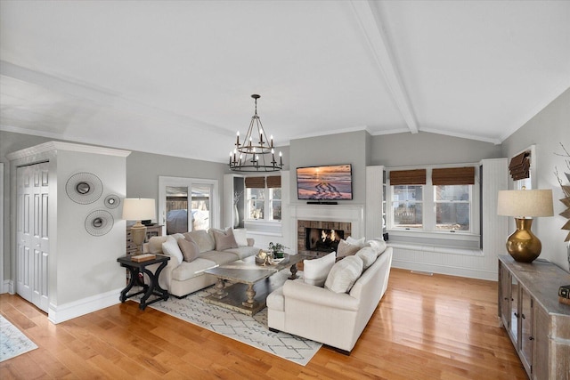 living area featuring lofted ceiling with beams, light wood-type flooring, a fireplace, and baseboards