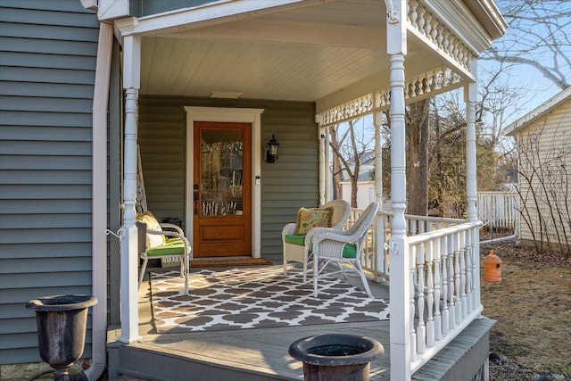 doorway to property featuring covered porch and fence