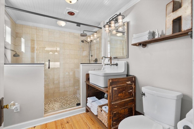 bathroom with toilet, a stall shower, a sink, and wood finished floors