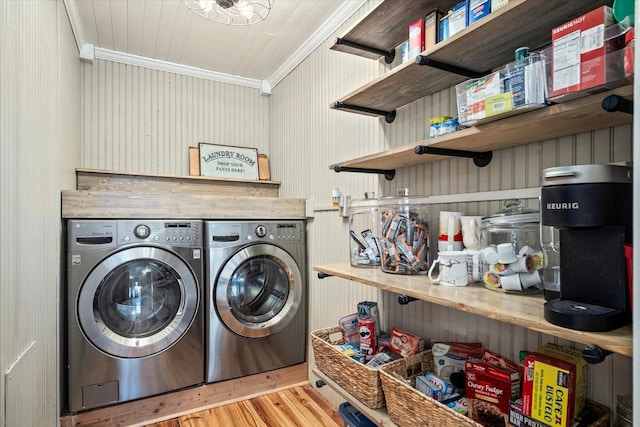 laundry area with laundry area, wood finished floors, washing machine and clothes dryer, and crown molding