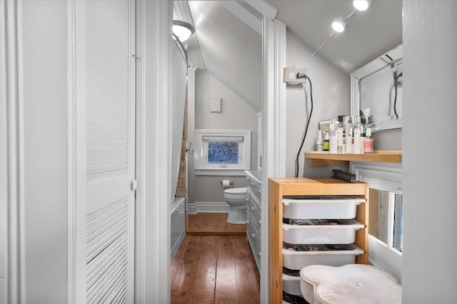 bathroom with baseboards, hardwood / wood-style floors, toilet, and shower / bathtub combination with curtain