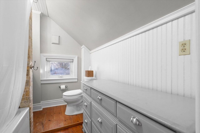 full bathroom with toilet, baseboards, vaulted ceiling, and hardwood / wood-style floors