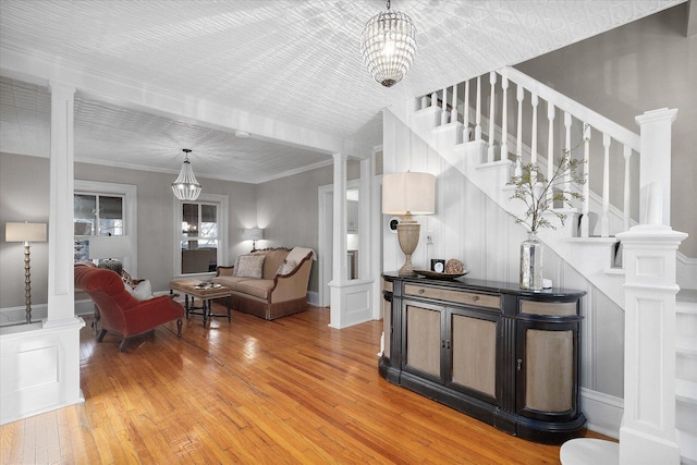 interior space with light wood-type flooring, decorative columns, stairway, and ornamental molding