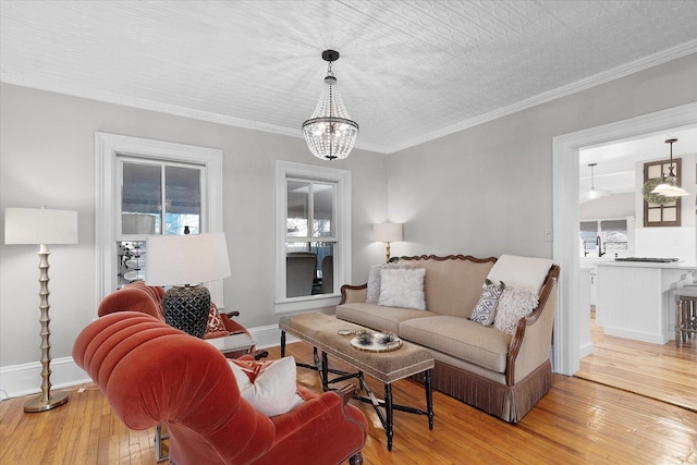 living area with light wood-style floors, baseboards, and crown molding