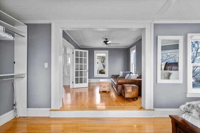 interior space featuring ceiling fan, crown molding, baseboards, and wood finished floors