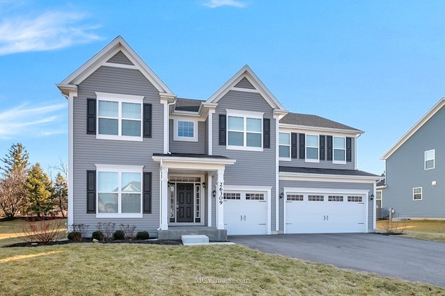 traditional home with an attached garage, aphalt driveway, and a front yard