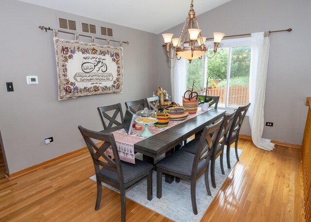 kitchen featuring vaulted ceiling, stainless steel appliances, light wood finished floors, and white cabinetry