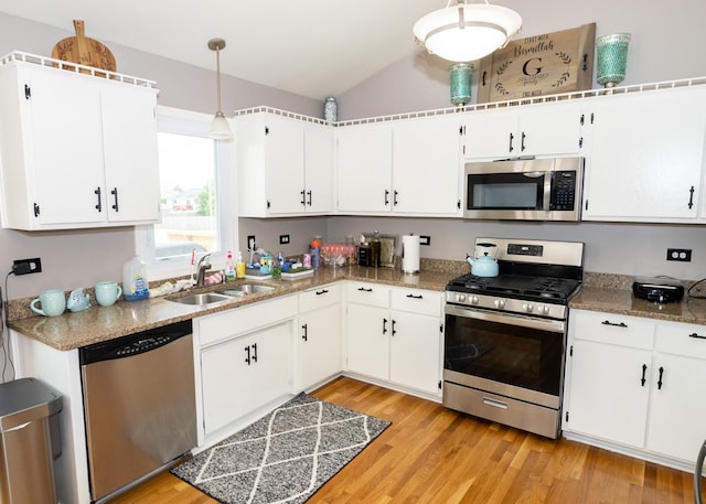 kitchen featuring lofted ceiling, light wood-style flooring, stainless steel appliances, a sink, and white cabinetry