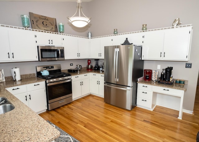 kitchen with white cabinets, light wood-style flooring, light stone counters, stainless steel appliances, and a sink