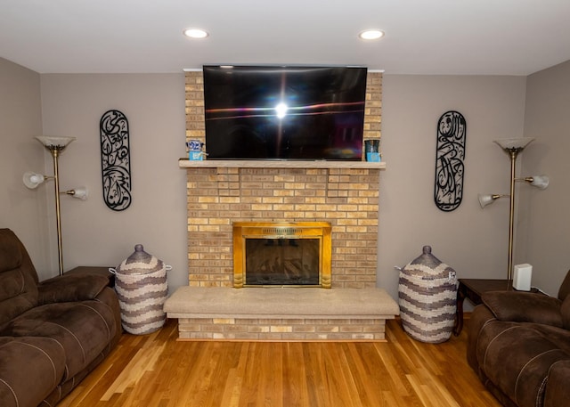 living area with recessed lighting, a fireplace, and wood finished floors