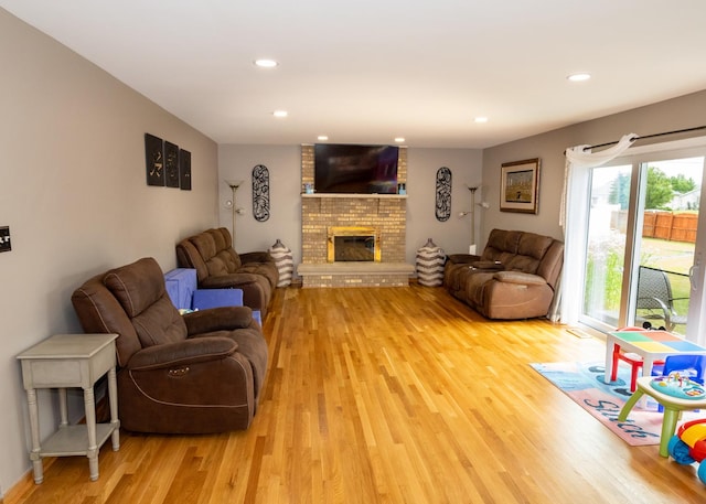 living area with light wood-type flooring, a brick fireplace, and recessed lighting