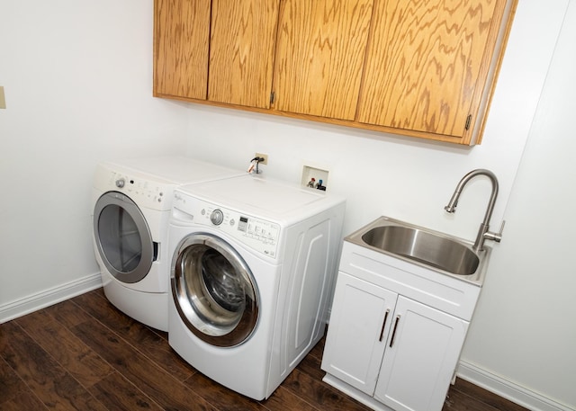 laundry room with cabinet space, baseboards, washer and clothes dryer, dark wood-type flooring, and a sink