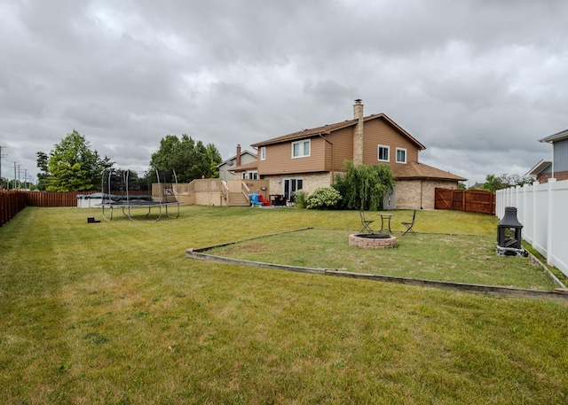 view of yard featuring a fenced backyard, a trampoline, and a fire pit