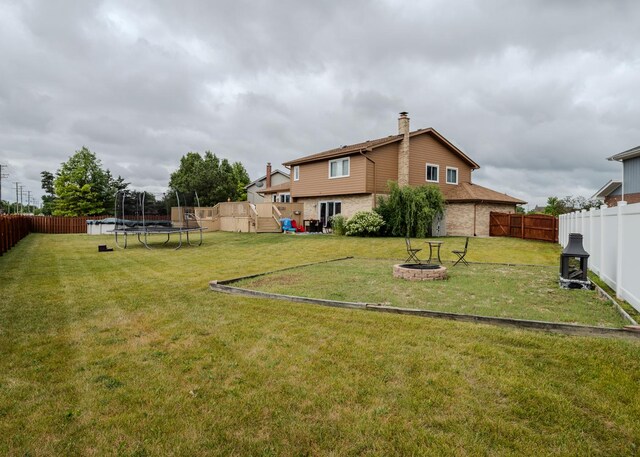 rear view of property featuring brick siding, a yard, a chimney, a patio area, and a deck