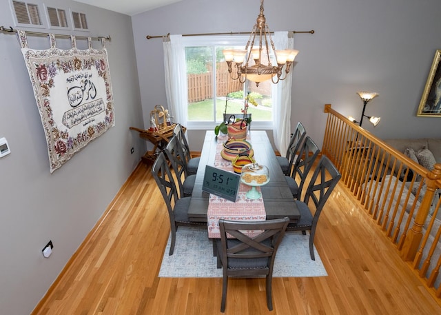 dining area featuring baseboards, wood finished floors, visible vents, and a notable chandelier