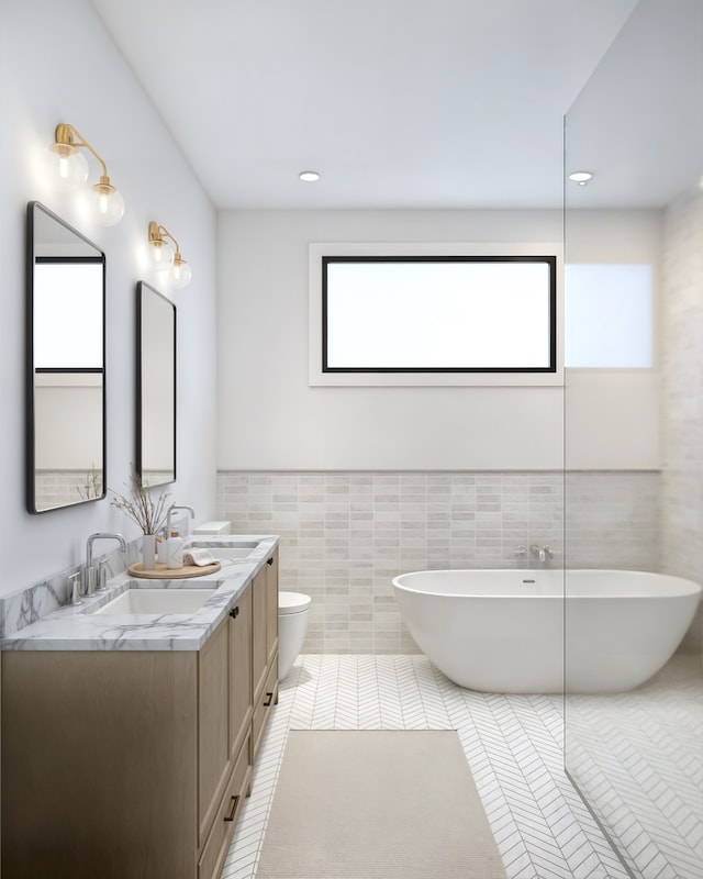 full bath featuring a soaking tub, tile patterned flooring, a sink, and tile walls