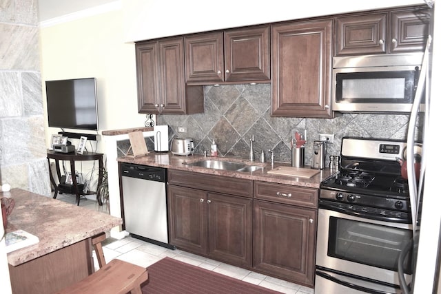 kitchen with a sink, light stone counters, tasteful backsplash, stainless steel appliances, and dark brown cabinetry