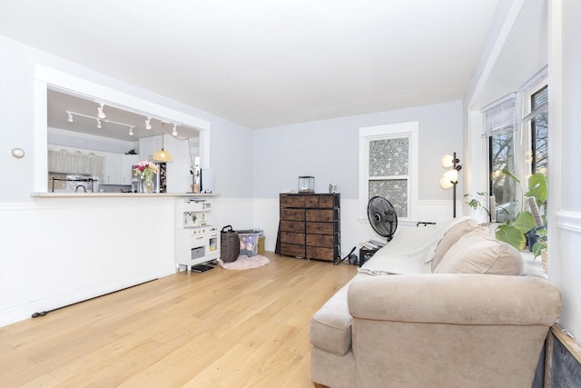 living area featuring rail lighting, wainscoting, and wood finished floors