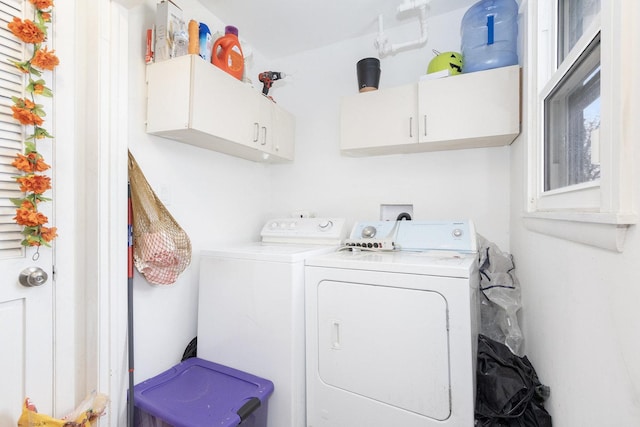 clothes washing area with washing machine and dryer and cabinet space