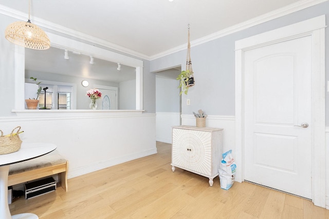 interior space with ornamental molding, wood finished floors, and rail lighting