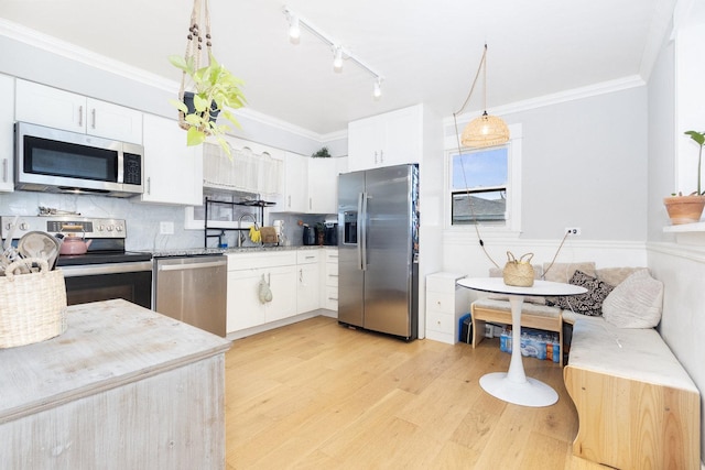 kitchen featuring appliances with stainless steel finishes, light wood-type flooring, a sink, and crown molding