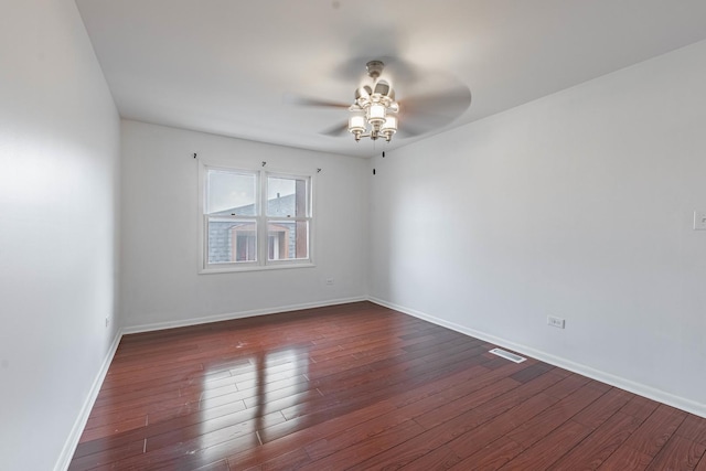 empty room featuring dark wood-style floors, baseboards, visible vents, and a ceiling fan