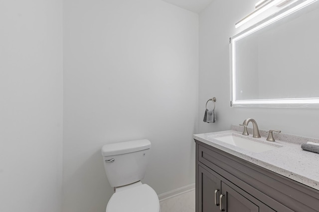 half bath featuring vanity, toilet, and baseboards