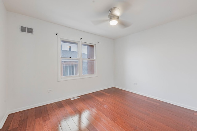 empty room featuring baseboards, wood-type flooring, visible vents, and a ceiling fan