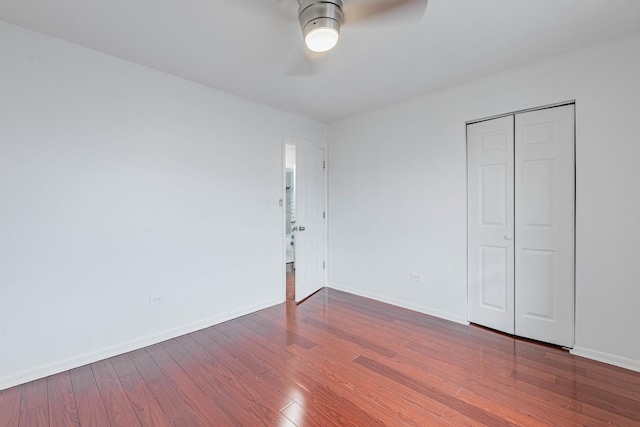 unfurnished bedroom with a ceiling fan, a closet, baseboards, and wood finished floors