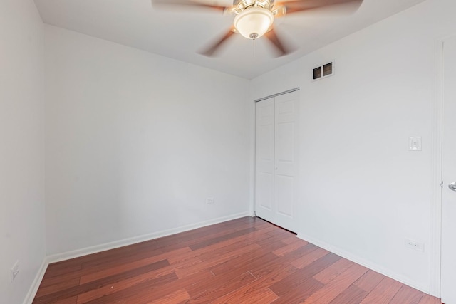 unfurnished room with ceiling fan, wood finished floors, visible vents, and baseboards