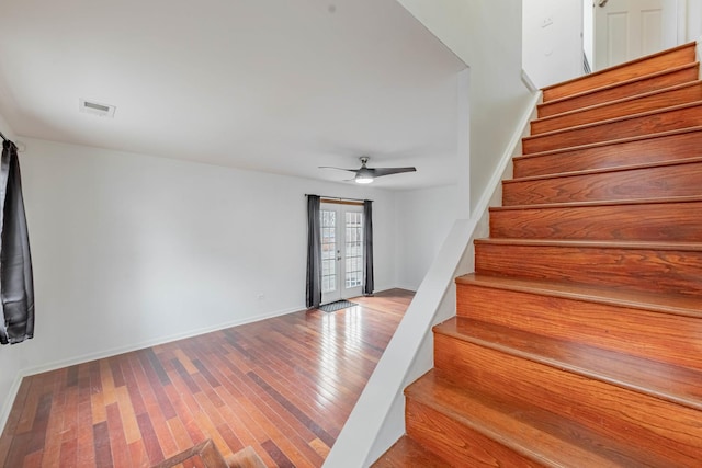 stairway with french doors, visible vents, hardwood / wood-style floors, a ceiling fan, and baseboards