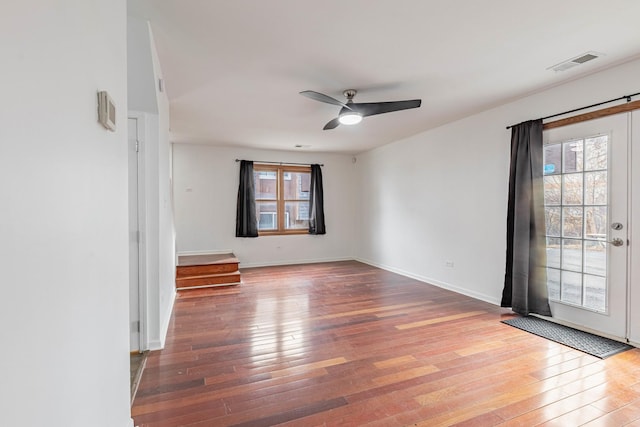 spare room featuring ceiling fan, wood-type flooring, visible vents, and baseboards