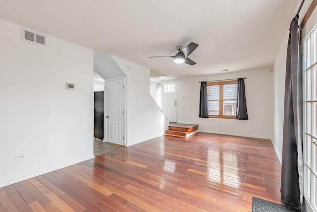 spare room with visible vents, baseboards, hardwood / wood-style flooring, ceiling fan, and stairs