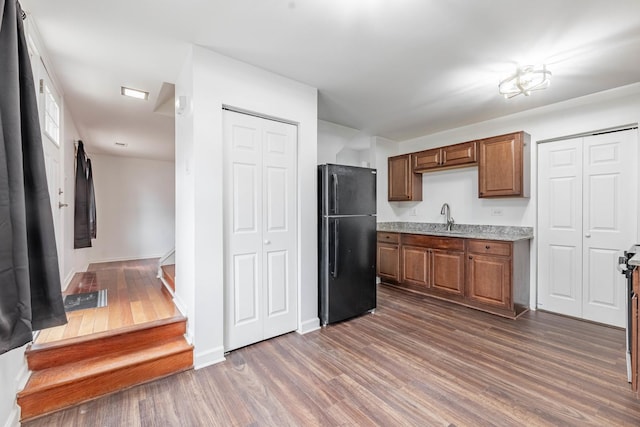 kitchen with dark wood-type flooring, freestanding refrigerator, light countertops, and a sink