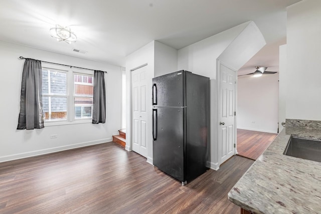 kitchen with dark wood-style floors, freestanding refrigerator, visible vents, and baseboards