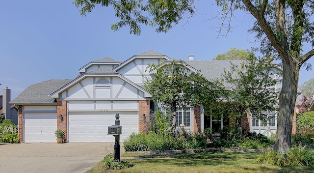 english style home featuring a garage, concrete driveway, brick siding, and roof with shingles